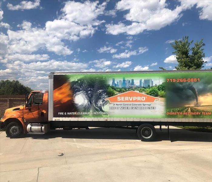 A large semi truck branded with SERVPRO logo and storm pictures
