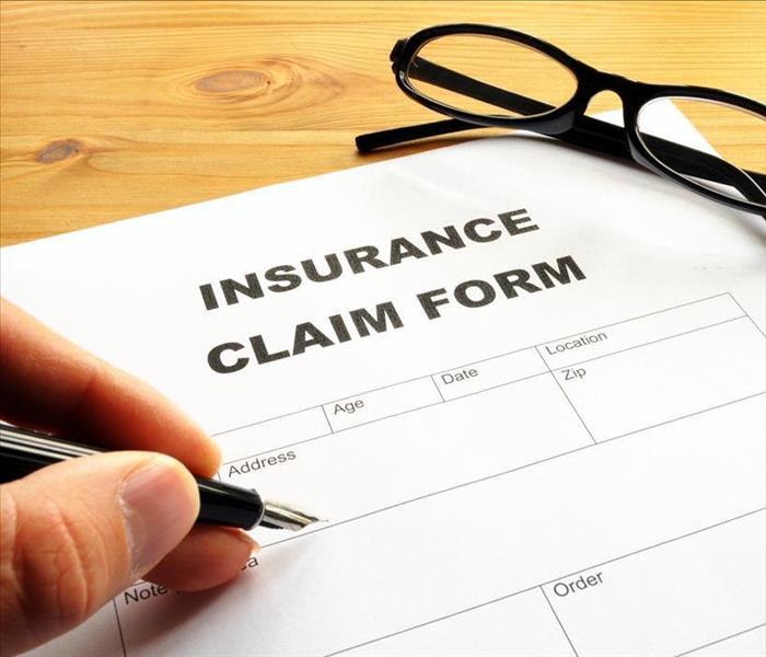 Image of an insurance claim form and a hand filling in the form.